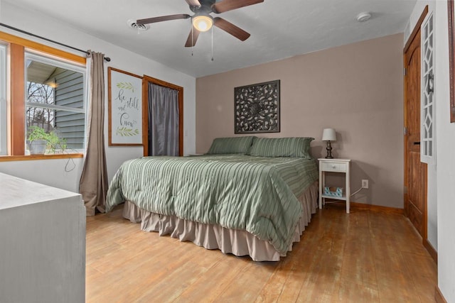 bedroom with hardwood / wood-style floors, baseboards, visible vents, and ceiling fan