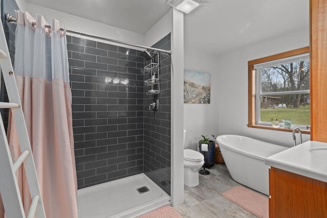 bathroom featuring toilet, visible vents, a freestanding tub, a shower stall, and vanity