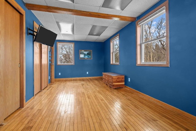 unfurnished room featuring hardwood / wood-style flooring, baseboards, and a drop ceiling