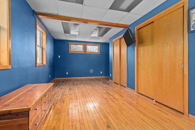 interior space featuring hardwood / wood-style floors, baseboards, and a paneled ceiling