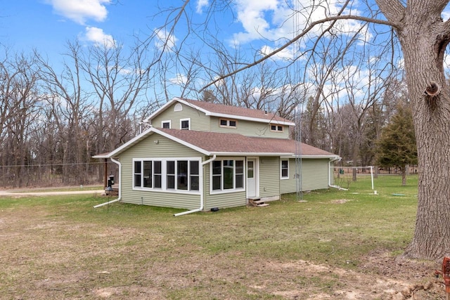 rear view of property with fence, a shingled roof, entry steps, and a yard