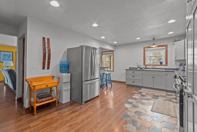 kitchen with a textured ceiling, a sink, stainless steel appliances, dark wood-style floors, and recessed lighting