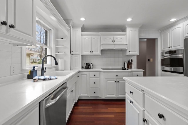 140 River Dr, Appleton, WI 54915 - kitchen with stainless steel appliances, a sink, dark wood-style flooring, backsplash, and white cabinetry