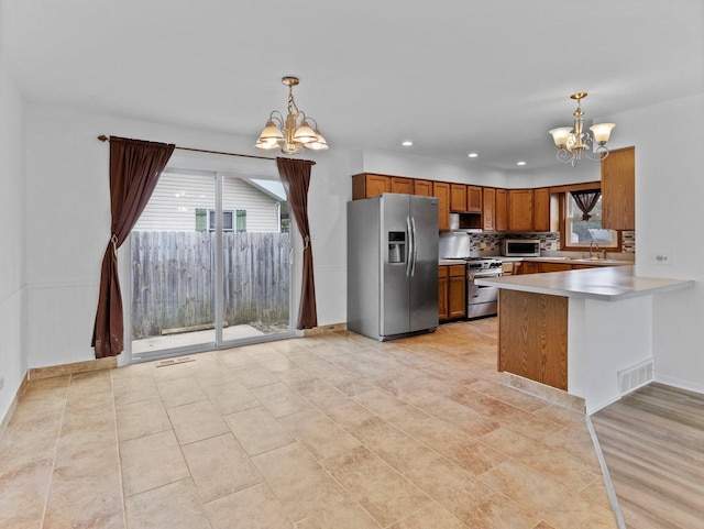 4155 Finch Ln, Delavan, WI 53115 - kitchen featuring brown cabinetry, a notable chandelier, stainless steel appliances, and a healthy amount of sunlight