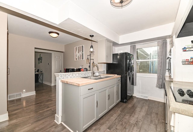 kitchen with a peninsula, visible vents, a sink, and dark wood-style flooring
