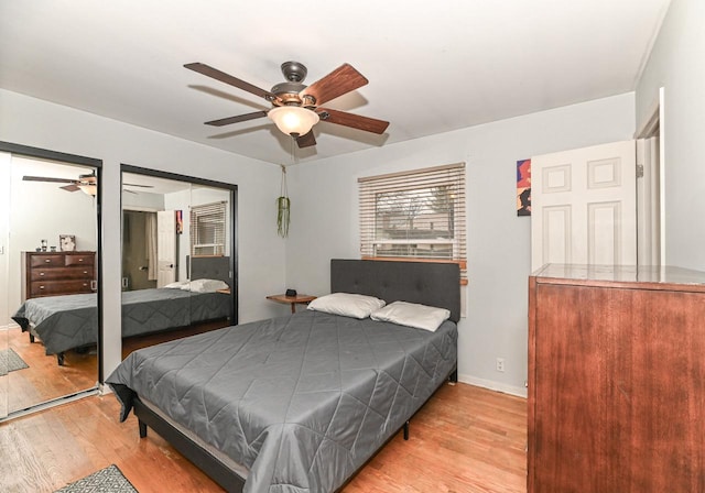 bedroom with light wood-style floors, two closets, a ceiling fan, and baseboards