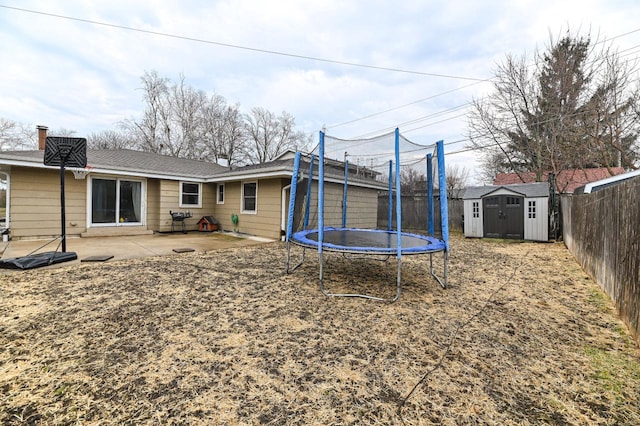 view of yard featuring a storage shed, an outbuilding, a fenced backyard, a trampoline, and a patio