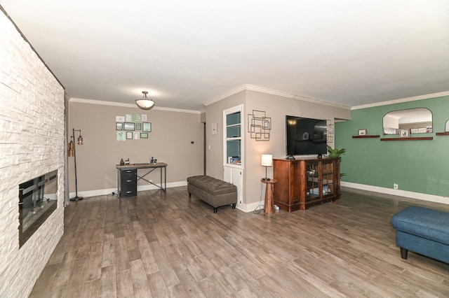living area with a fireplace, wood finished floors, crown molding, and baseboards