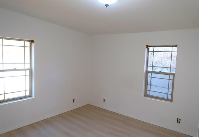 spare room with light wood-style flooring, a wealth of natural light, and baseboards