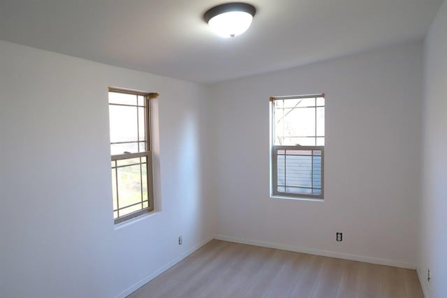 spare room featuring baseboards and light wood-style floors
