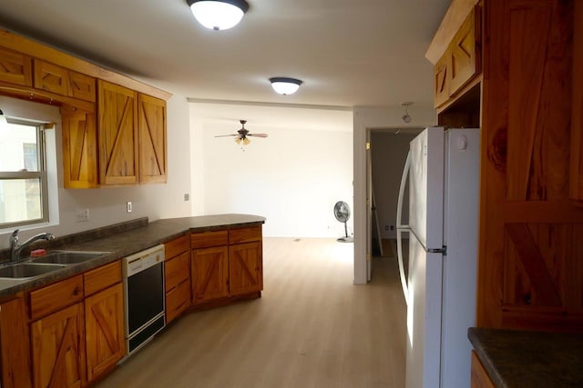kitchen with dishwasher, brown cabinets, a sink, and freestanding refrigerator