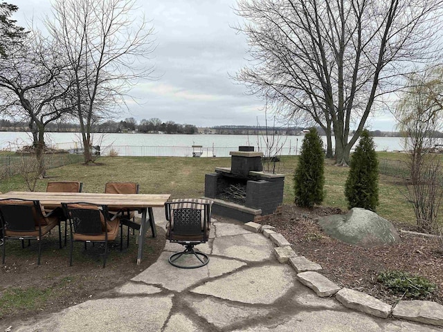 view of patio / terrace featuring fence, outdoor dining space, and a water view
