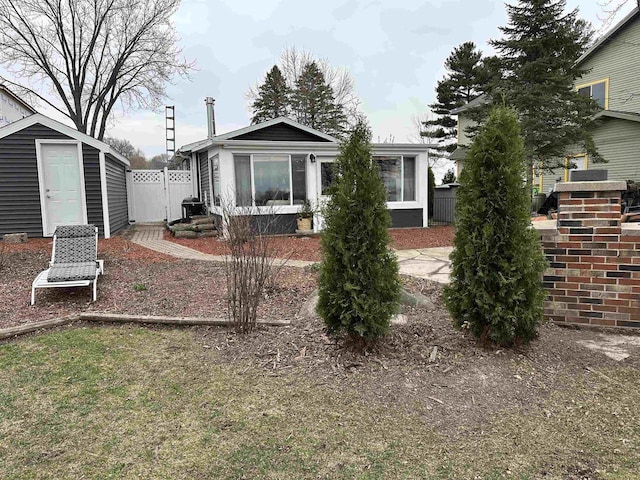 rear view of property with an outdoor structure, fence, and a storage unit
