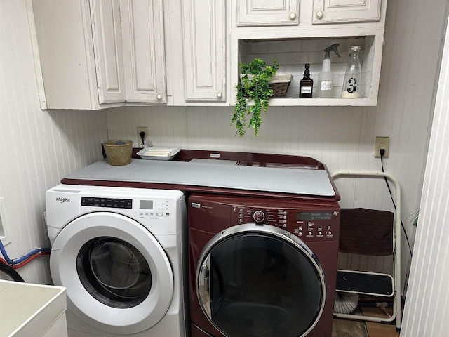 laundry area with wooden walls, a sink, washer and clothes dryer, and cabinet space