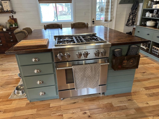kitchen with high end stainless steel range, light wood-style floors, wood walls, and wooden counters