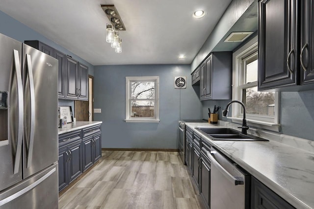 kitchen featuring a sink, light wood-type flooring, baseboards, appliances with stainless steel finishes, and recessed lighting