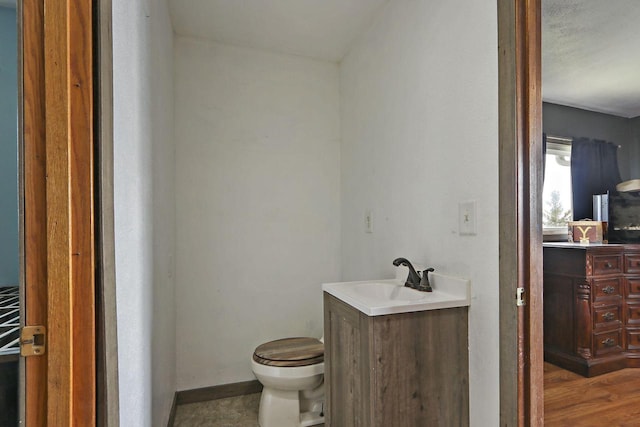 bathroom featuring baseboards, vanity, and toilet