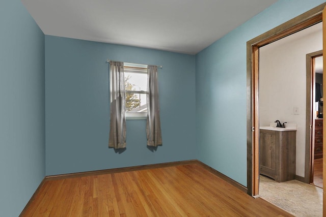 empty room with wood finished floors and a sink