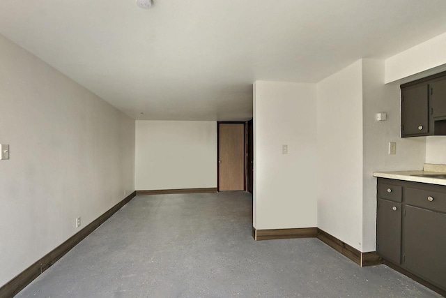 interior space with light countertops, a sink, baseboards, finished concrete flooring, and open floor plan