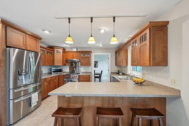 5407 Marsh Woods Dr, Mcfarland, WI 53558 - kitchen featuring appliances with stainless steel finishes, a peninsula, brown cabinetry, glass insert cabinets, and a sink
