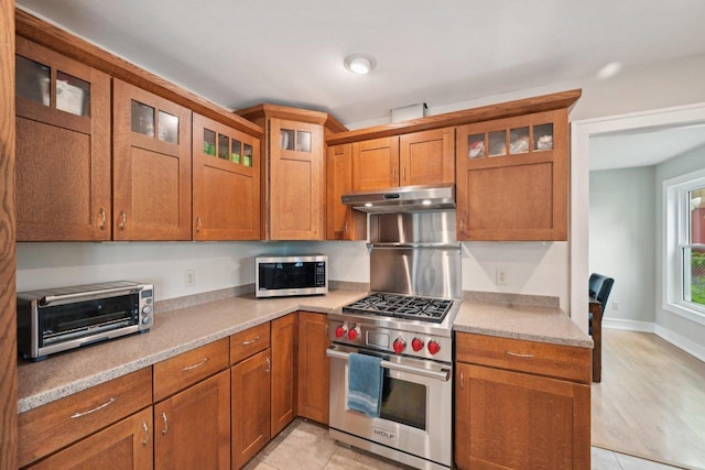 5407 Marsh Woods Dr, Mcfarland, WI 53558 - kitchen with appliances with stainless steel finishes, under cabinet range hood, brown cabinets, glass insert cabinets, and light tile patterned flooring