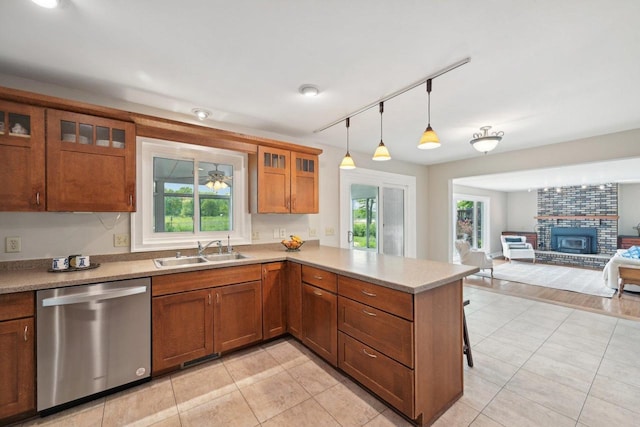 5407 Marsh Woods Dr, Mcfarland, WI 53558 - kitchen featuring dishwasher, a sink, a peninsula, brown cabinetry, and a brick fireplace
