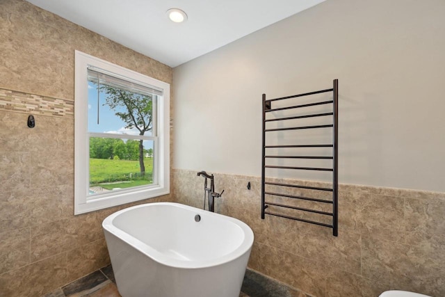 5407 Marsh Woods Dr, Mcfarland, WI 53558 - bathroom with tile walls, a freestanding tub, a towel warmer, a wainscoted wall, and radiator