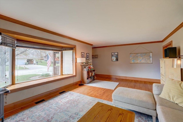 living room featuring ornamental molding, baseboards, visible vents, and wood finished floors