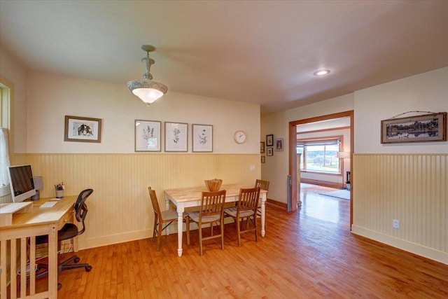 dining area featuring light wood-style flooring, baseboards, and a wainscoted wall