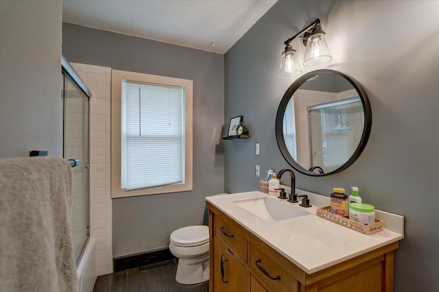 bathroom featuring bath / shower combo with glass door, toilet, wood finished floors, and vanity