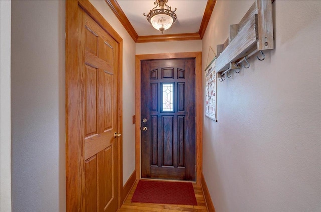 doorway featuring wood finished floors, baseboards, and ornamental molding