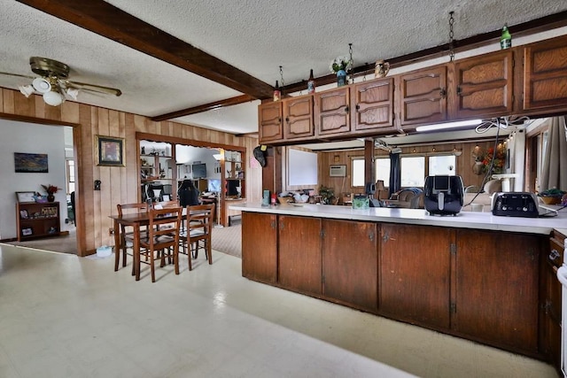 203 S Main St, Deerfield, WI 53531 - kitchen featuring a ceiling fan, a textured ceiling, light countertops, wood walls, and beam ceiling