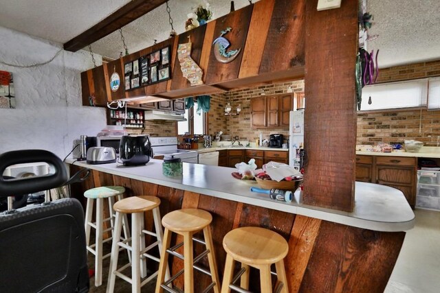 203 S Main St, Deerfield, WI 53531 - kitchen with a textured ceiling, white appliances, brick wall, beamed ceiling, and light countertops