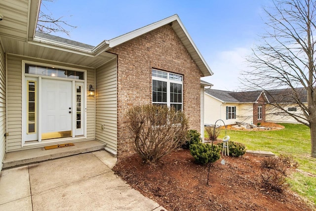 doorway to property featuring a lawn and brick siding