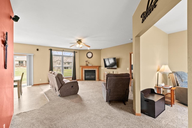 carpeted living room with a glass covered fireplace and ceiling fan