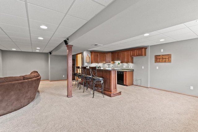 kitchen featuring a peninsula, a paneled ceiling, open floor plan, light colored carpet, and a breakfast bar