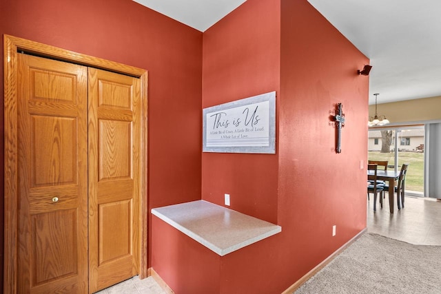 corridor with an inviting chandelier and baseboards