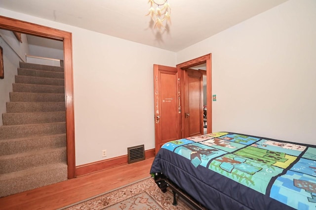 bedroom featuring light wood-style floors, visible vents, and baseboards