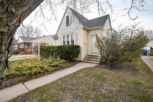 bungalow-style house with roof with shingles and entry steps