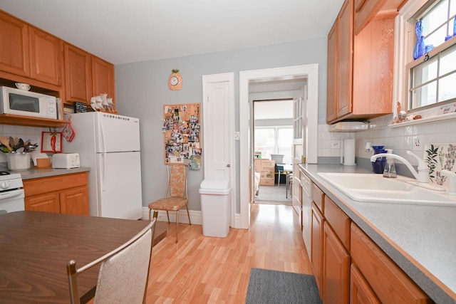 kitchen featuring white appliances, a wealth of natural light, light wood-style floors, and tasteful backsplash