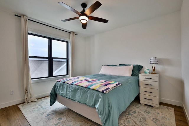 bedroom with ceiling fan, baseboards, and light wood-type flooring