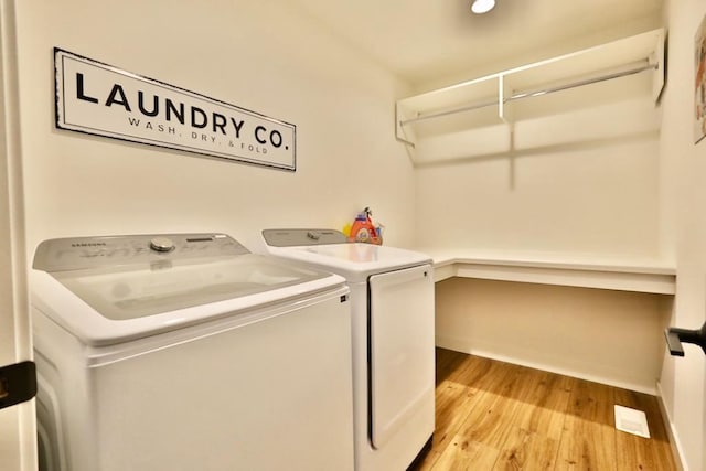clothes washing area featuring washing machine and dryer, baseboards, light wood finished floors, and laundry area