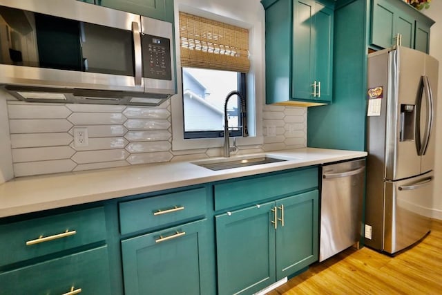 kitchen featuring appliances with stainless steel finishes, green cabinets, and a sink