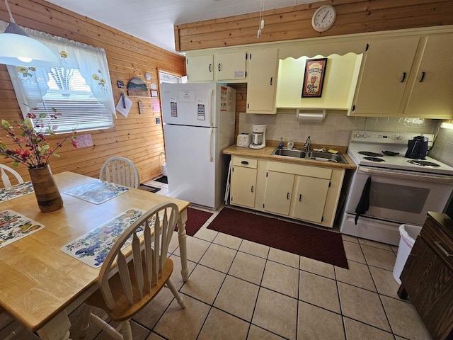 kitchen with wood walls, decorative backsplash, white appliances, and a sink