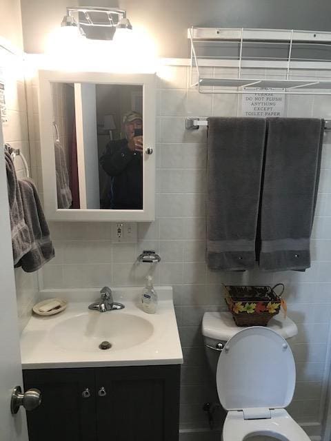 bathroom featuring tile walls, toilet, and vanity