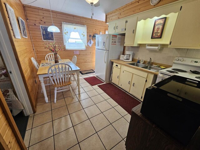 kitchen featuring a sink, decorative backsplash, wood walls, white appliances, and light countertops
