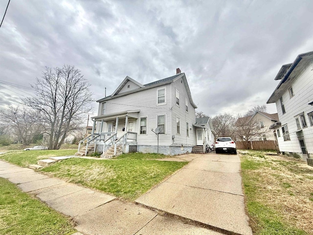 view of front of property with concrete driveway, a front lawn, fence, and a porch