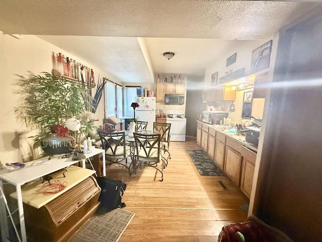 kitchen with light wood finished floors, light countertops, white appliances, and a textured ceiling