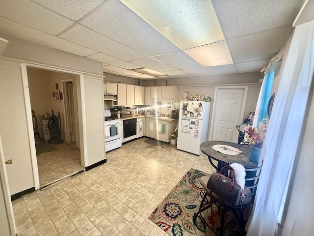 kitchen featuring a drop ceiling, under cabinet range hood, light floors, light countertops, and white appliances