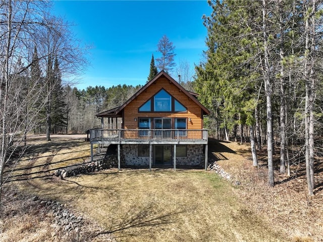 5044 Clayton Rd, Winter, WI 54896 - back of house with faux log siding, stone siding, a wooded view, a wooden deck, and a lawn